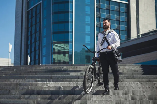 Brodaty biznesmen, niosąc jego rower na schodach — Zdjęcie stockowe