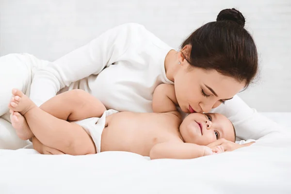 Matka całuje jej słodkie adorable baby w łóżku — Zdjęcie stockowe