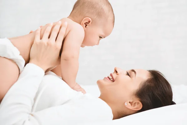 Young mom holding her happy baby in air — Stock Photo, Image