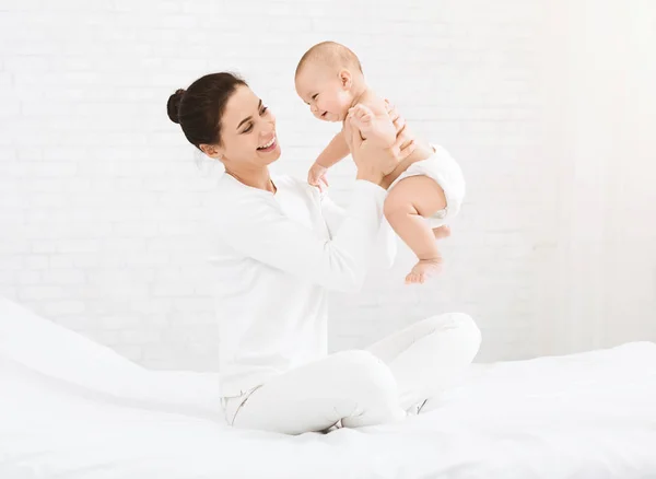 Ung mamma håller hennes happy baby i luften — Stockfoto