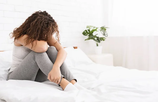 Mladá žena v depresi sedí doma na posteli — Stock fotografie