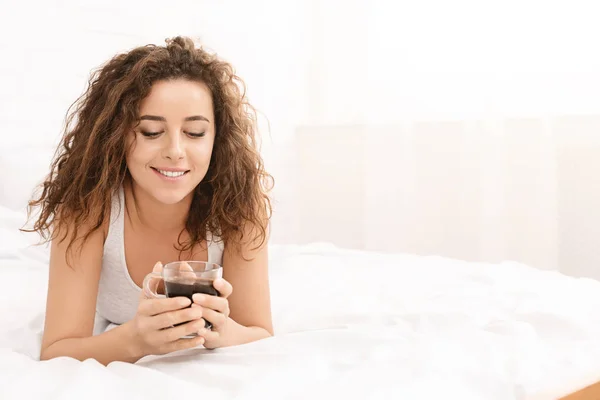 Молода жінка розслабляється на ліжку з кавою — стокове фото