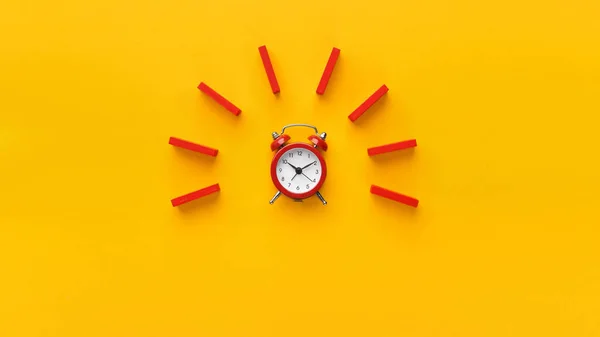 Reloj despertador con dominó rojo sobre fondo amarillo — Foto de Stock