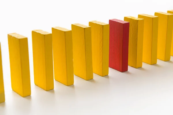 Rode houten blok tussen rij van gele ones — Stockfoto