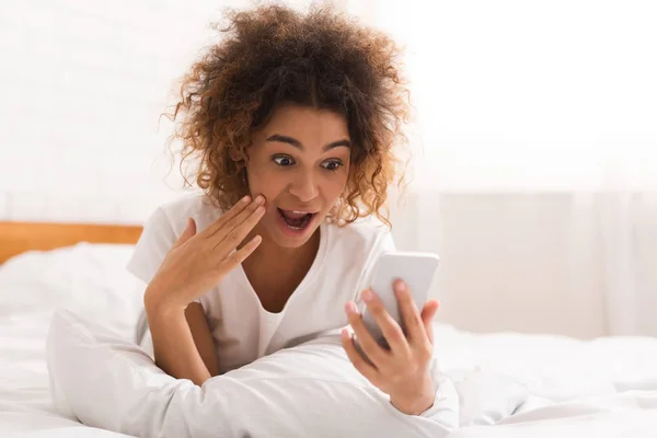 Mujer sorprendida leyendo el mensaje en el teléfono en casa —  Fotos de Stock