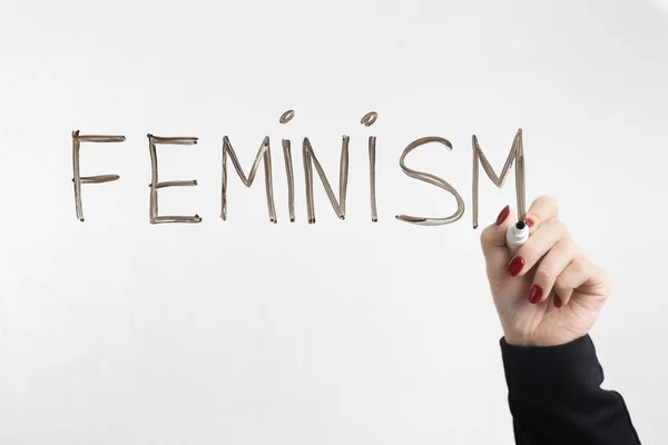 Φεμινισμός λέξη γραμμένη σε γυαλί πίνακα με γυναικείο χέρι — Φωτογραφία Αρχείου