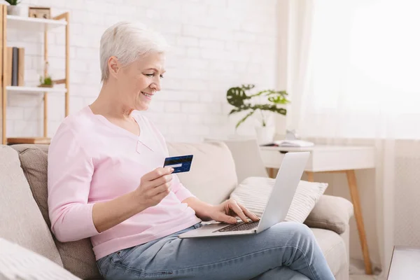 Зріла жінка купує онлайн з кредитною карткою і ноутбуком — стокове фото