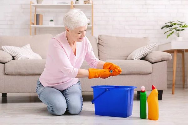 Lächelnd reif hausfrau putzen boden bei zuhause — Stockfoto