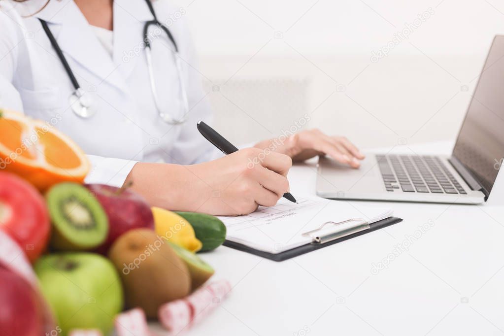 Doctor working with laptop and writing on paperwork