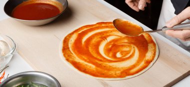 İtalyan pizza hazırlık. Şef temel pizza sosu ekleme