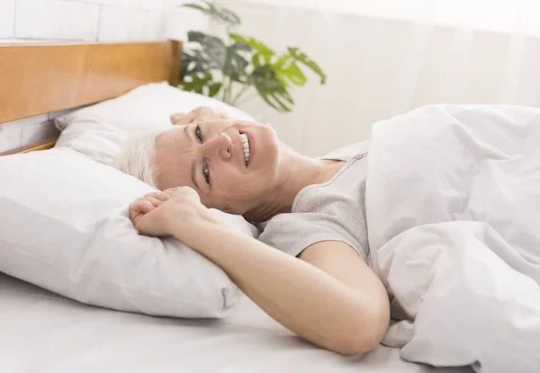Reife Frau legt sich zu Hause in ihr Bett — Stockfoto