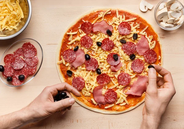 Köchin macht leckere Pizza und dekoriert sie mit Oliven — Stockfoto