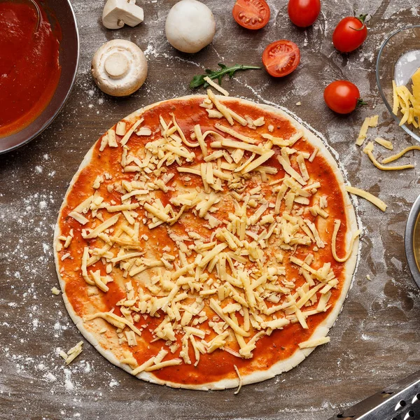 Pizza-Zubereitung, geriebener Käse und Zutaten — Stockfoto