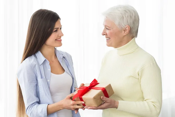 Senior mother receiving gift from adult daughter — Stock Photo, Image