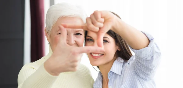 Mère et fille aînée faisant le cadre avec les doigts — Photo