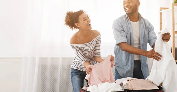 Pareja afroamericana empacando ropa en la maleta en casa — Foto de Stock