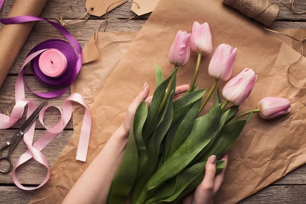 Mulher florista fazendo buquê de tulipas na mesa de madeira — Fotografia de Stock