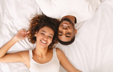 Genç seven çift yan yana yatakta yatarken ve kameraya bakıyor