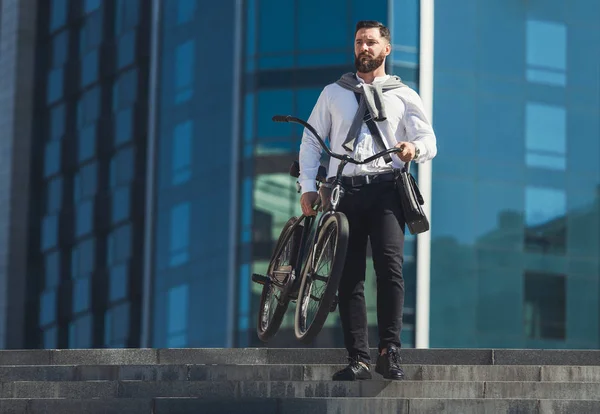 Bonito homem de negócios carregando sua bicicleta nas ruas da cidade — Fotografia de Stock