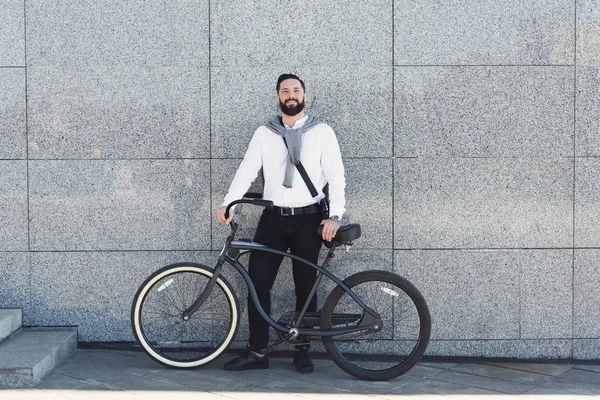 Geschäftsmann steht mit Fahrrad gegen Hauswand. — Stockfoto