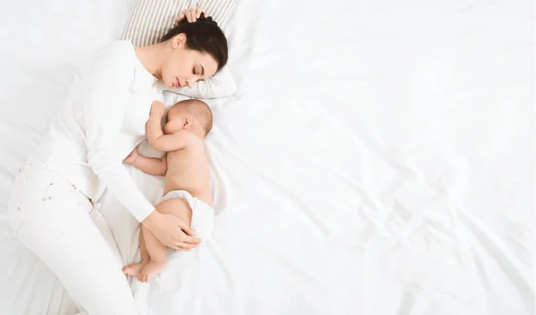 Ung mamma och hennes söta baby som sover i sängen — Stockfoto