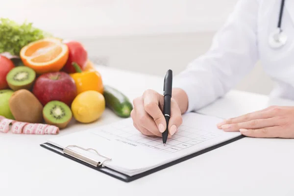 Nutricionista femenina médico escribir plan de dieta vegetal —  Fotos de Stock