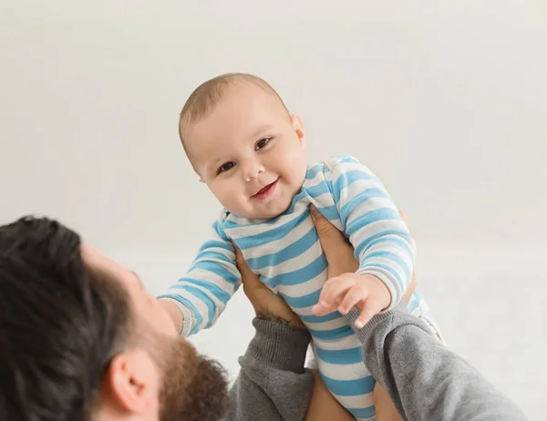 Dad holding happy baby son up in the air — Stock Photo, Image