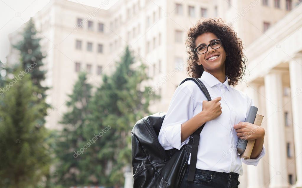 Smiling afro student with backpack and books outdoor
