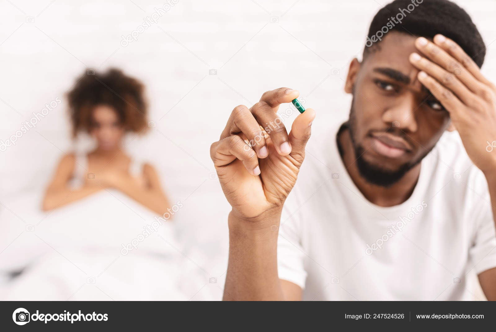 Upset black guy taking potency pill before sex with girlfriend Stock Photo by ©Milkos 247524526
