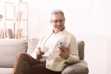 Smartphone kullanarak ve kahve içme olgun adam