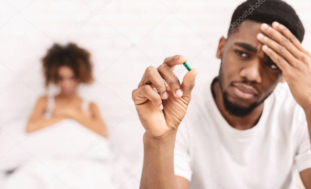 Upset black guy taking potency pill before sex with girlfriend