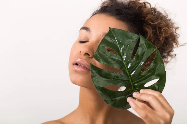 Girl with tropical leaf covering half of face — Stock Photo, Image