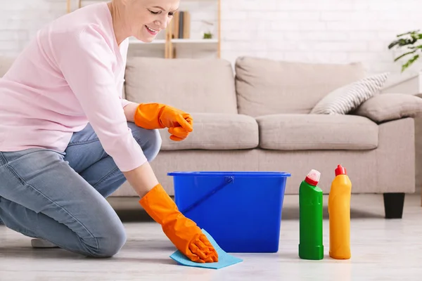 Χαμογελώντας ώριμη νοικοκυρά καθαρισμού δαπέδου στο σπίτι — Φωτογραφία Αρχείου