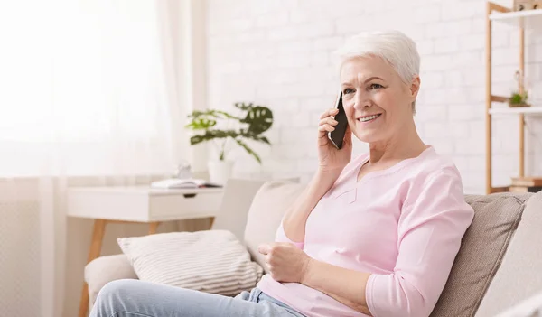 Starší žena mluvila na její mobilní telefon doma — Stock fotografie