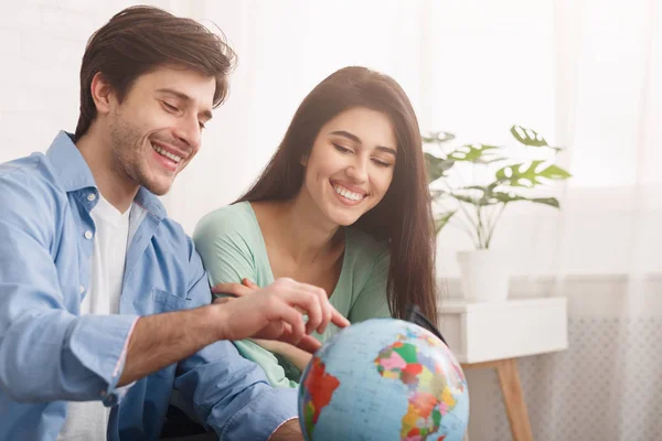 Glückliches Paar schaut auf Globus, wählt Land zu besuchen — Stockfoto