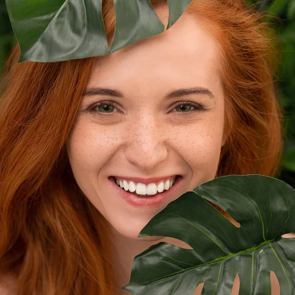 Mujer joven con sonrisa perfecta con hojas tropicales —  Fotos de Stock