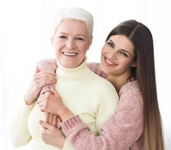 Feliz madre e hija abrazando y mirando a la cámara — Foto de Stock