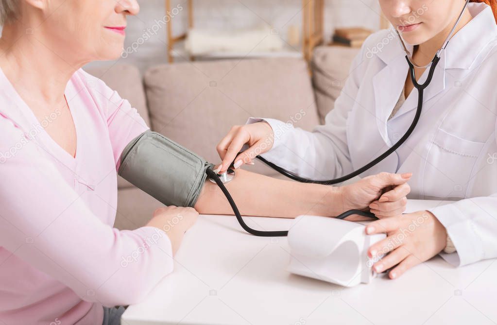 Doctor checking blood pressure of senior patient