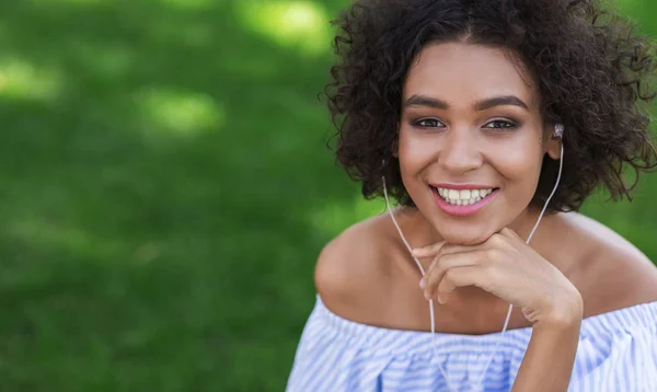 Excited black woman listening to music outdoors
