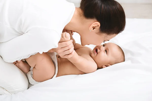 Young woman playing with her little baby in bed — Stock Photo, Image