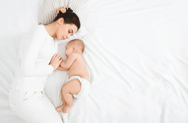 Ung mamma och hennes söta baby som sover i sängen — Stockfoto