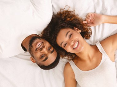 Genç seven çift yan yana yatakta yatarken ve kameraya bakıyor