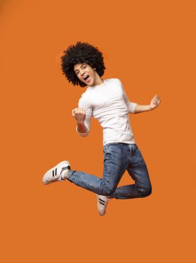 Mutlu siyah adam turuncu zemin üzerine atlama