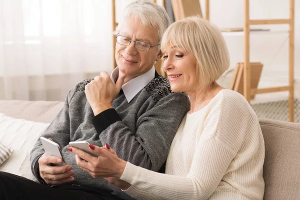 Pareja mayor con smartphones, viendo fotos en casa — Foto de Stock