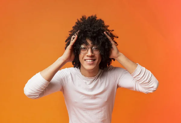 Surprised young curly-haired black guy clutching his head, — Stock Photo, Image
