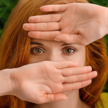 Beautiful young redhead woman hiding behind hands clipart
