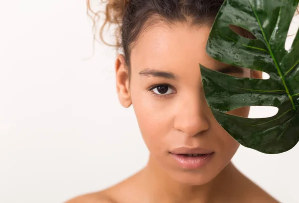 Afro-Amerikaanse vrouw met groene tropische blad, lichte achtergrond — Stockfoto