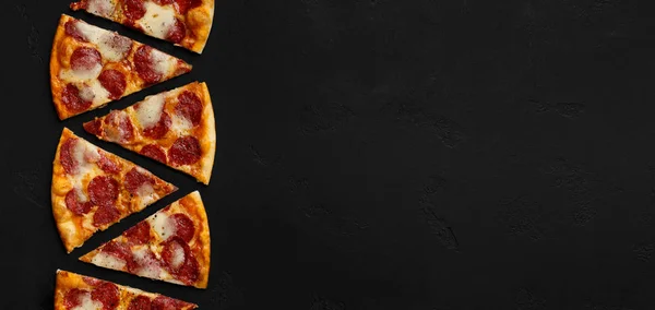 Deliciosas rebanadas de pizza con salami sobre fondo negro — Foto de Stock