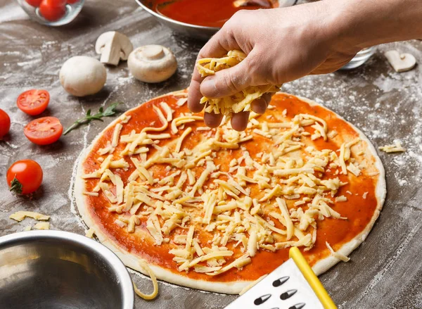 Mann bestreut Küche mit Pizza und Käse — Stockfoto