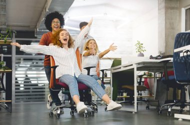 Ofis koltukları üzerinde yarış ve gülümseyen genç neşeli iş adamları